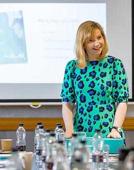 A face2faceHR franchisee stands at an event with a banner smiling to camera