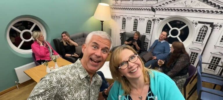 Two people smiling in foreground with others in background. Support for HR consultants