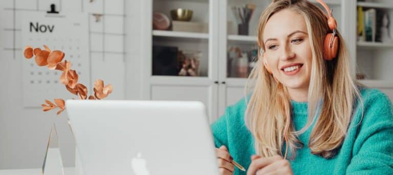 Woman sitting by a laptop with headphones on - hybred HR strategy