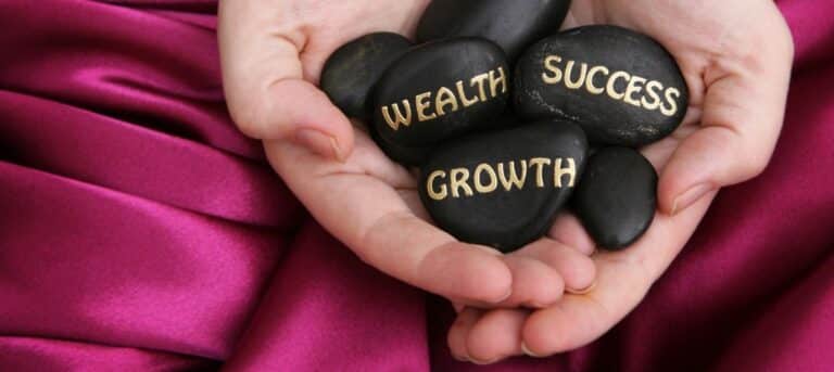 Photo of hands holding three stones, 'wealth', 'success' and 'growth' for hr consultancy growth plan