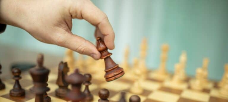 Picture of a person's hand about to move a chess piece on a chess board depicting moving into HR consultancy