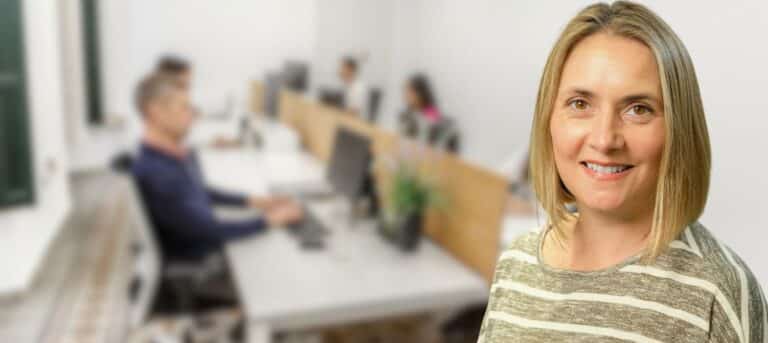 An image of a face2faceHr consultant with a number of blurred people sitting at desks in the background - hr support for smes