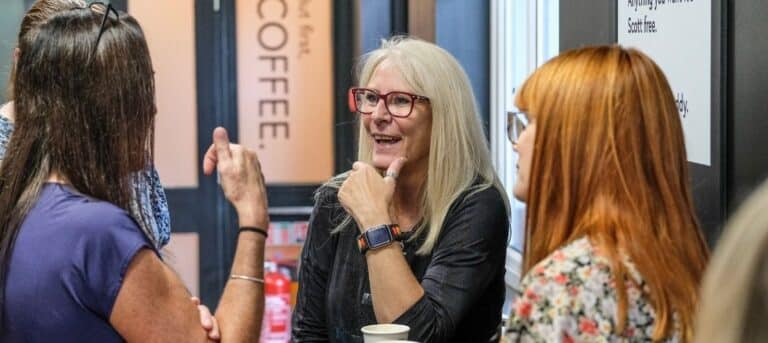 Image of a group of women talking around a table - networking as an hr consultant