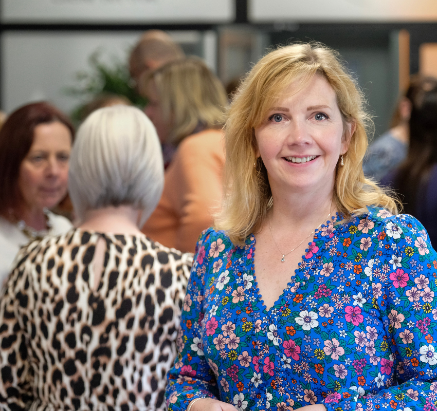 Eleaner Deem stands in front of a presentation at a conference meeting smiling